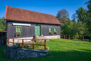 a small house with a green door and a fence at Šajnska Hiža, autentična goranska kuća u prirodi in Brod Moravice