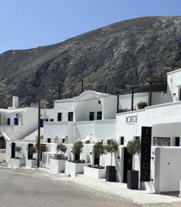 eine Reihe weißer Gebäude mit einem Berg im Hintergrund in der Unterkunft Nostos Apartments Kamari in Kamari