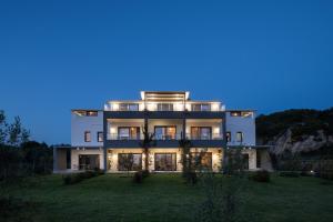 Un grand bâtiment blanc avec des lumières allumées la nuit dans l'établissement Villa Miranda Roshi, à Toroni