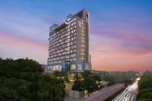a rendering of a tall building with a sunset at Novotel New Delhi City Centre in New Delhi