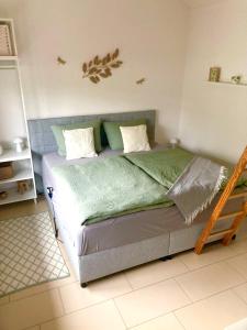 TinyHouse Pfalzperle Auszeit nahe Deutsche Weinstraße & Therme في Ellerstadt: غرفة نوم بسرير وملاءات ووسائد خضراء