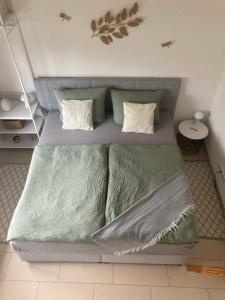 TinyHouse Pfalzperle Auszeit nahe Deutsche Weinstraße & Therme في Ellerstadt: سرير بملاءات ومخدات خضراء في الغرفة