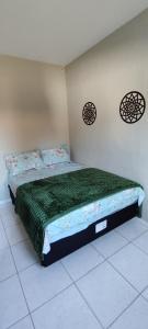 a bedroom with a bed with a green comforter at Aconchego na Praia em Palhoça in Palhoça