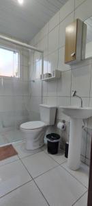 a white bathroom with a toilet and a sink at Aconchego na Praia em Palhoça in Palhoça +19 photos