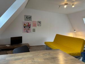 a living room with a yellow couch and a television at See You 2 in Germersheim