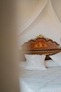 a bed with a wooden headboard and white pillows at Rigat Park & Spa Hotel - Adults Recommended in Lloret de Mar