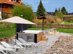 a patio with a hot tub and chairs and an umbrella at Birkholmhof in Bärnau