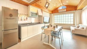 a kitchen with a refrigerator and a table with chairs at Sokcho Seohyeon Ine Pension in Sokcho