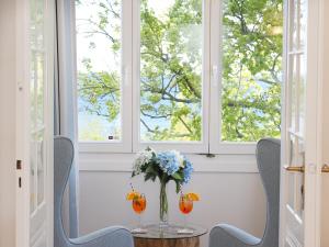 einen Tisch mit einer Vase aus Blumen und zwei Fenstern in der Unterkunft Strandvillen Heringsdorf in Heringsdorf