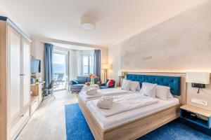a bedroom with a large bed with a blue headboard at Strandhotel Löchnerhaus in Reichenau