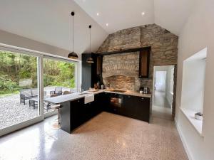 a kitchen with a large stone wall and a table at River Cottage Retreat Hideaway Sauna Sligo Leitrim in Sligo +38 photos