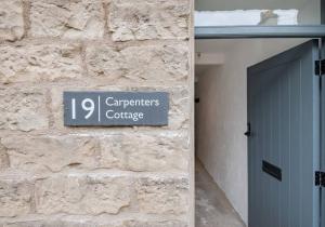 ein Schild an der Seite eines Gebäudes mit einer Tür in der Unterkunft Carpenters Cottage - The Lakes! in Kendal