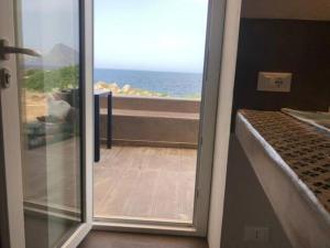 una porta che conduce a un balcone con vista sull'oceano di SUN KISSED a Tonnara di Bonagia