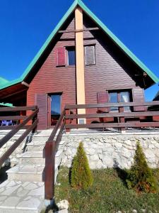 une grande maison rouge avec un escalier en face de celle-ci dans l'établissement Mountain Lodge with View near Durmitor National Park, à Tepačko Polje