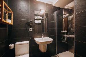 a black tiled bathroom with a sink and a toilet at Hotel Zaragoza Plaza in Donostia-San Sebastián +35 photos