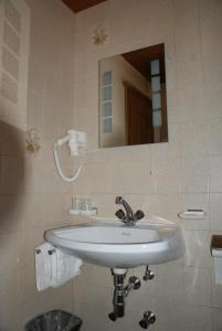 ein Badezimmer mit einem weißen Waschbecken und einem Spiegel in der Unterkunft Hotel Garni Maximilian in Zell am Ziller