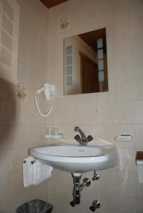 a bathroom with a white sink and a mirror at Hotel Garni Maximilian in Zell am Ziller