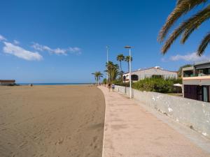 einen Sandstrand mit Palmen und Bürgersteig in der Unterkunft Ciaboga Front Line By CanariasGetaway in San Agustín