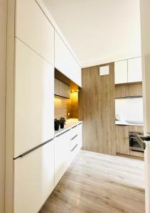 cocina con armarios blancos y suelo de madera en RÓŻANA Poznań free parking, en Poznan 6 fotos más