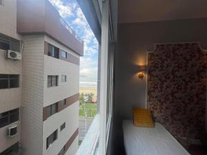 a bedroom with a bed and a window with a view at Vista Lateral Mar Fique No Melhor Lugar da Praia in São Vicente