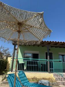 a large straw umbrella sitting on a chair in front of a house at Veaki Beach House in Xanthi