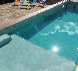 a swimming pool with blue water and some chairs at Apartamento dos Arcos in Teresópolis