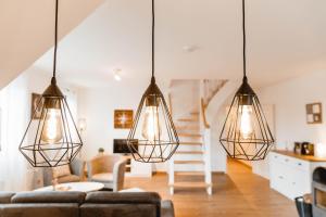 a living room with three lights hanging from the ceiling at Huxfeld-Hof - Wümme in Grasberg