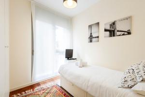 a white bedroom with a bed and a tv at Duplex Las Margas Vistas Montañas in Sabiñánigo
