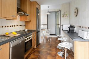 a kitchen with a sink and a counter with stools at Duplex Las Margas Vistas Montañas in Sabiñánigo