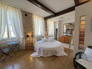 een slaapkamer met een bed met witte lakens en ramen bij Sweet Home Cornelia in Bruniquel