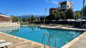 a swimming pool with chairs and a building in the background at Duplex Las Margas Vistas Montañas in Sabiñánigo