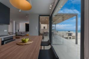 een keuken en eetkamer met een tafel en uitzicht op de oceaan bij Blue Haven Villa in Polykhrono