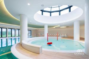 una grande piscina in un edificio con soffitto di Apartament Premium Baltic View-Pinea Apartments Pobierowo-morze na wyciągnięcie ręki!-dostęp do strefy basenów,saun i jacuzzi-SANNEL Apartments for rent a Pobierowo