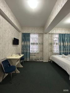 a bedroom with a bed and a desk and a bed and curtains at Айымхан in Almaty