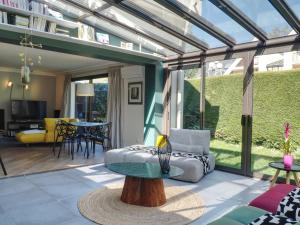 a conservatory with a glass extension with a table and a couch at Beau 4 pièces avec grand jardin et tennis proche HEC et INRAE in Jouy-en-Josas