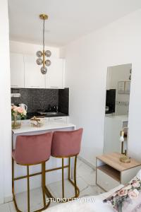 a kitchen with white cabinets and pink chairs at Lazuli Seaview Apartments 2Bdr in Larnaka