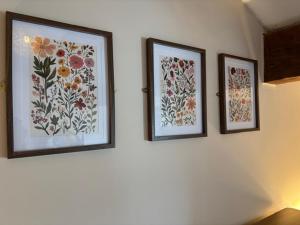 three pictures of flowers are hanging on a wall at The Shippon Barn - A delightful haven for families in Wirral