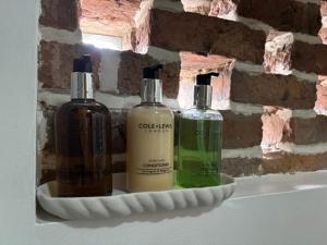 three bottles of soap on a shelf next to a brick wall at The Shippon Barn - A delightful haven for families in Wirral