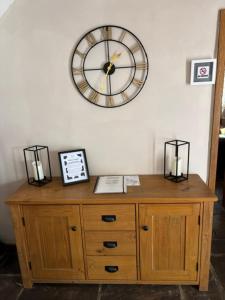 a clock on a wall above a wooden cabinet at The Shippon Barn - A delightful haven for families in Wirral