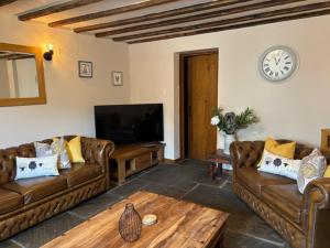 a living room with leather couches and a tv at The Shippon Barn - A delightful haven for families in Wirral