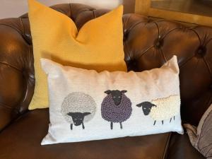 a pillow with three sheep on a couch at The Shippon Barn - A delightful haven for families in Wirral