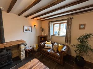 a living room with a leather couch and a fireplace at The Shippon Barn - A delightful haven for families in Wirral