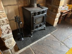 a stove sitting in a room next to a brick wall at The Shippon Barn - A delightful haven for families in Wirral