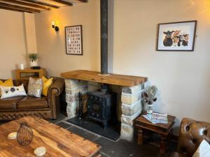 a living room with a fireplace and a couch and a table at The Shippon Barn - A delightful haven for families in Wirral