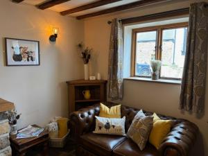 a living room with a leather couch and a window at The Shippon Barn - A delightful haven for families in Wirral