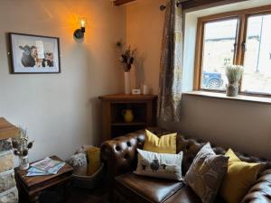 a living room with a leather couch and a window at The Shippon Barn - A delightful haven for families in Wirral