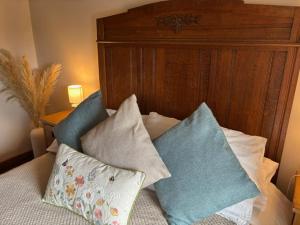 a bed with three pillows and a wooden headboard at The Shippon Barn - A delightful haven for families in Wirral
