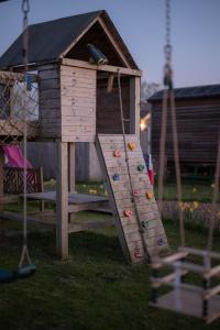 a wooden playground with a slide in a yard at The Shippon Barn - A delightful haven for families in Wirral