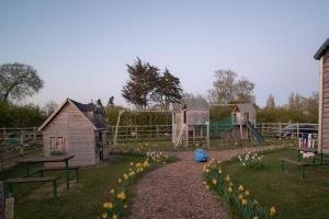 a park with a playground with flowers in the grass at The Shippon Barn - A delightful haven for families in Wirral