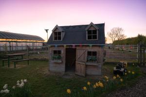 a small house in a yard with flowers at The Shippon Barn - A delightful haven for families in Wirral
